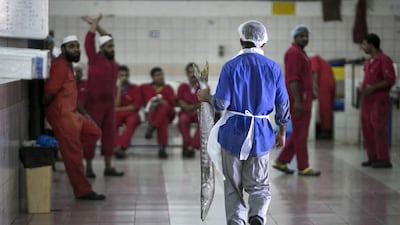 A fish seller walks toward the fish cutters, who take turns to prepare the selected fish for the customers in Abu Dhabi. Silvia Razgova / The National