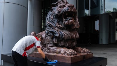 A worker cleans a statue of a lion in front of the HSBC Holdings Plc headquarters building in Hong Kong. Bloomberg