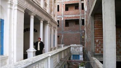 Moncef Ben Rhouma stands in front of his building (left). The new building (right) nearly touches the old building in some places, in violation of local building codes.
