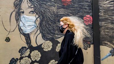 A pedestrian wearing a protective mask walks past a mural in San Francisco, California. Bloomberg