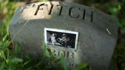 A dog’s headstone, with a tile photo of 'Bob' and his owner.