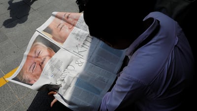 A journalist reads a local newspaper showing an article on the summit between US President Donald Trump and North Korean leader Kim Jong Un near St. Regis hotel in Singapore. Tyrone Siu / Reuters