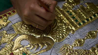 An artist draws lines on gold foil