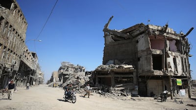 Iraqis pass destroyed buildings in the old city of Mosul, eight months after Iraqi government forces retook the city from the control of ISIL / AFP