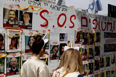 People wearing costumes for the Jewish holiday of Purim pass by a wall with photos of hostages held in the Gaza Strip on March 24, 2024 in Tel Aviv, Israel. Getty Images.