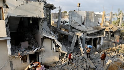 Palestinians carry belongings near their damaged house following Israeli strikes in Khan Younis, in southern Gaza, on Wednesday. Reuters