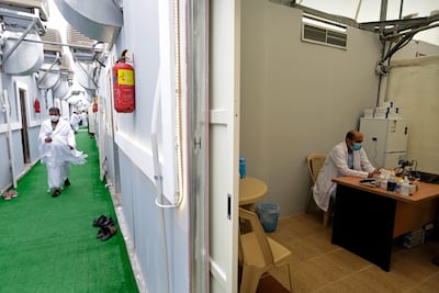 A Muslim pilgrim walks in the corridor of a tent camp as a doctor works in a camp clinic in Mina, in 2021. AP