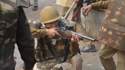 A police personnel aims his gun towards protesters during demonstrations against India's new citizenship law in Meerut. AFP