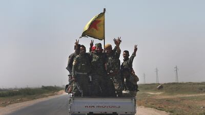 US-backed Syrian Democratic Forces fighters stand on their pickup as they flash victory signs on a road that links to Raqqa city on July 26, 2017. AP / Hussein Malla