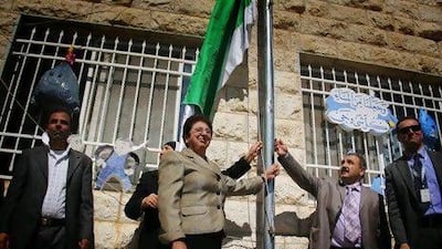 Mayor Janet Mikhail raises a flag with male community leaders to honour a school for its efforts in being environmentally friendly.