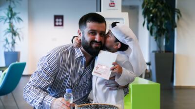 Rozik hugs Sharifi Behruzi, his guardian, after receiving his golden visa. Khusnum Bhandari / The National