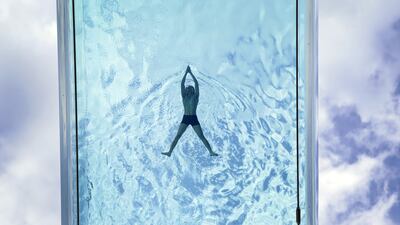 A man swims in the Sky Pool, a transparent swimming pool suspended 35 metres above ground between two apartment buildings, during hot weather in Nine Elms, central London. PA