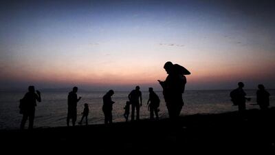 Syrian refugees use mobile phones to communicate with their relatives minutes after arriving by dinghy on the Greek island of Kos on August 20, 2015. Yannis Kolesidis/EPA