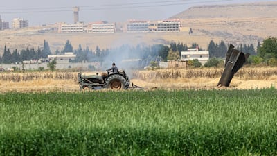 A Syrian farmer drives a tractor past the remains of an Iranian ballistic missile that landed in a field near the Najha, in the Damascus countryside. EPA