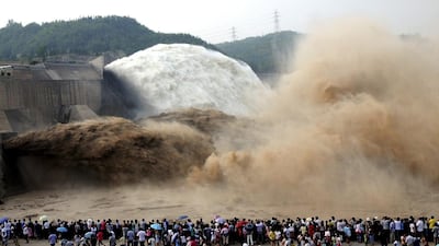 People look on as water gushes from the Xiaolangdi Reservoir section on the Yellow River, during a sand-washing operation in Jiyuan, Henan province. Reuters
