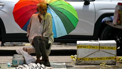 A fish vendor waiting for customers takes shade under an umbrella on a hot summer afternoon in New Delhi on May 29, 2024, amid ongoing heatwave. Temperatures in India's capital have soared to a record-high 49. 9 degrees Celsius (121. 8 degrees Fahrenheit) as authorities warn of water shortages in the sprawling mega-city. (Photo by Arun SANKAR / AFP)