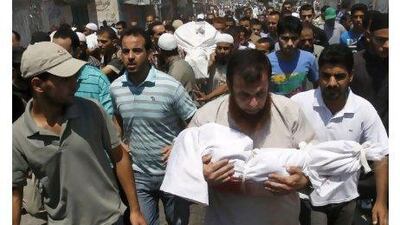 A Palestinian mourner carries the body of two-year-old Malek Shaat, who they say was killed in an Israeli air raid in August. Hatem Moussa / AP Photo