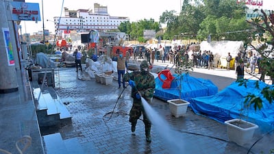 Iraqi health officials and Civil Defense staff wearing protective suits spray disinfectant as a precaution against the coronavirus in the commercial markets in Najaf, Iraq, AP