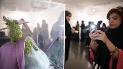 A visitor takes a photo of ‘Nested Love’, a miniature mannequin by Sumayyah al Suwaidi at the Ghaf Gallery. Silvia Razgova / The National