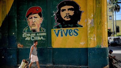 A Cuban passes by a graffiti depicting Venezuelan president Hugo Chavez (L) and Che Guevara in Havana, on July 12, 2017. / AFP PHOTO / YAMIL LAGE