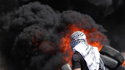 A Palestinian protester stands next to burning tyres during clashes with Israeli soldiers after a demonstration against illegal settlements near the West Bank city of Nablus. EPA
