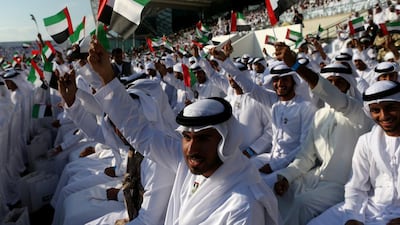 Emirati men wave the UAE flag ahead of the military parade.