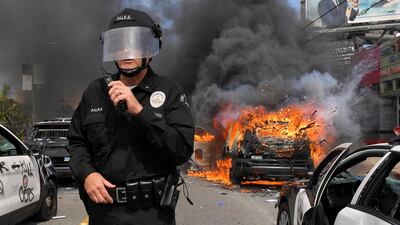 Los Angeles Police Department commander Cory Palka stands among several destroyed police cars as one explodes during a protest in Los Angeles. AP Photo