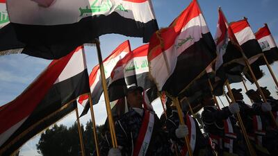 Iraqi policemen hold their national flag and march during a parade in Baghdad. AFP