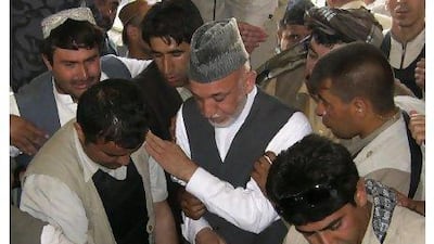 President Hamid Karzai, centre, attends the burial of his half brother Ahmed Wali Karzai in his family's ancestral village of Karz, in Kandahar province, Afghanistan, yesterday. AP Photo