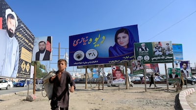 A boy walks past election posters of parliamentary candidates in Jalalabad. Reuters