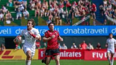 Dan Bibby of England, in white, out sprints the Wales defence, in red, to score the first points of their match on Day 2 at the Dubai Rugby Sevens. Victor Besa for The National