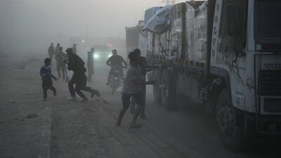 Palestinians left hungry by Israel's siege of the Gaza Strip run towards lorries carrying aid from the World Food Programme, in Deir Al Balah. AP