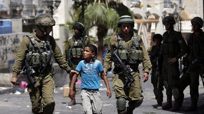 Israeli soldiers arrest a young Palestinian boy following clashes in the center of the West Bank town of Hebron, on June 20, 2014. Thomas Coex/ AFP