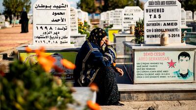 A woman mourns amidst tombs next to a funeral for two Syrian Democratic Forces (SDF) fighters in the Syrian Kurdish-majority city of Qamishli after they were killed by a Turkish military drone. AFP