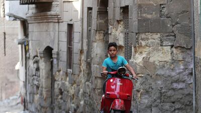 A boy rides a motorcycle past an old house at an alleyway in Darb al-Labbana hillside neighbourhood in Cairo, Egypt. Reuters