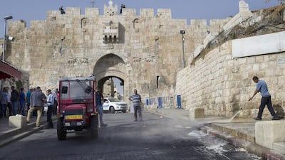 A worker hoses down the spot where a Palestinian man was shot dead by Israeli police on October 12, 2015, outside the Lion’s Gate entrance to the Muslim Quarter of Jerusalem’s Old City. Jim Hollander / EPA