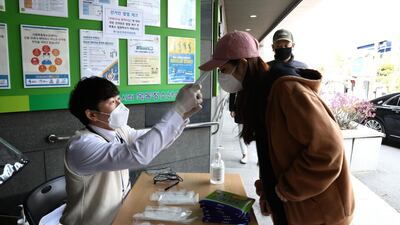 A South Korean woman has her temperature checked before casting her vote for the parliamentary elections in Seoul on April 15, 2020. Virus testing, social distancing and periodic lockdowns may be necessary for the next two years, a Harvard study suggested. Chung Sung-Jun / Getty Images