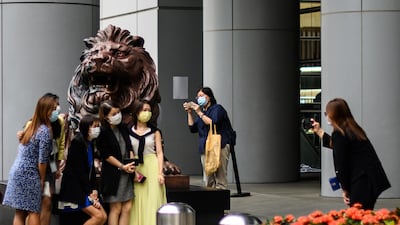 People pose for a photo next to a lion statue outside HSBC bank headquarters building in Hong Kong. AFP