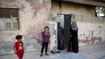 A Syrian family, who didn't flee their home, are pictured in the border Syrian town of Tal Abyad, on the fifth day of a Turkish offensive in Syria. Turkish forces and their proxies on Sunday seized Tal Abyad. AFP