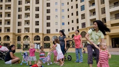 Nannies relax with their employers' children on a lawn outside Jumeirah Beach Residences in Dubai .