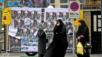 Iranian women chat in front of electoral posters. AFP