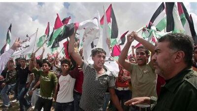 Hamas security officials confront Palestinians during a demonstration near the border line between Egypt and southern Gaza Strip yesterday. Israeli fire wounded 15 Palestinians during a demonstration in the Gaza Strip. Ali Ali / EPA
