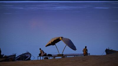 Two Indian men sit on the banks of the river Ganges at day break near one of the Ghats of Varanasi, India. Roberto Schimdt / AFP
