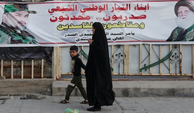 A woman walks past a banner showing Shiite cleric Moqtada Al Sadr, who is calling for a boycott of the election. Reuters