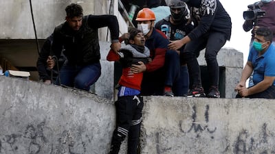 Demonstrators help a wounded young man after being hit by a stone during the ongoing anti-government protests in Baghdad. REUTERS