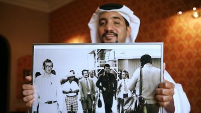 Ali Kaddas al Rumaithi holds a 1969 photograph of Muhammad Ali touring his father's greenhouses on Saadiyat Island during the boxer's visit to Abu Dhabi. Among those accompanying Ali is Mr al Rumaithi's father, Abdullah Kaddas al Rumaithi, in checkered shorts and white hat.