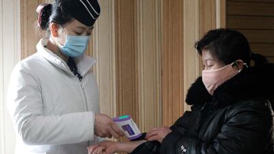 A staff member, left, of the Pongnam Noodle House checks the body temperature of a woman coming into its restaurant in Pyongyang, North Korea. AP Photo