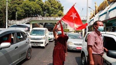 A Buddhist monk waves the flag of deposed Myanmar leader Aung San Suu Kyi's National League for Democracy party in the middle of a street in Yangon, Myanmar. AP