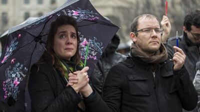 A woman, grasping a symbolic pencil, is moved to tears as people gather in front of Notre Dame cathedral for a minute of silence in memory of the 12 victims in the January 7, 2015, massacre at the Paris headquarters of satirical magazine Charlie Hebdo. Ian Langsdon / EPA / January 8, 2015
