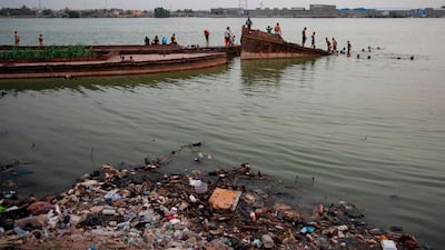 Iraqi youths play atop a sunken boat in front of amid rubbish floating in the Shatt Al Arab river in the southern port city of Basra. AFP